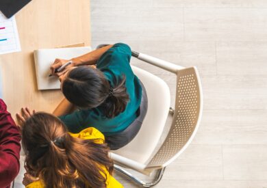 An image of team working together at a desk over a laptop