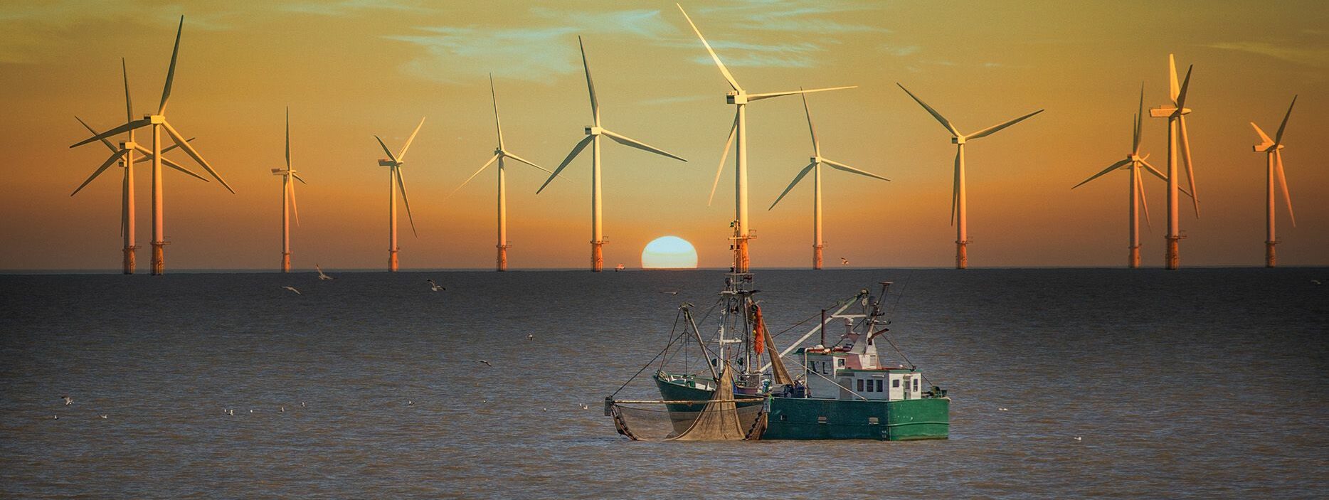 An image of a boat sailing by a wind farm