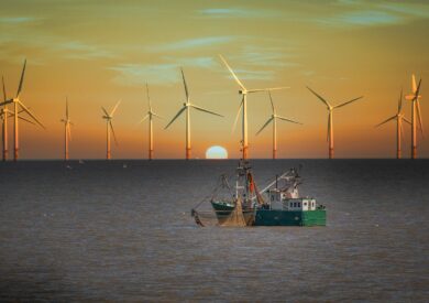 An image of a boat sailing by a wind farm