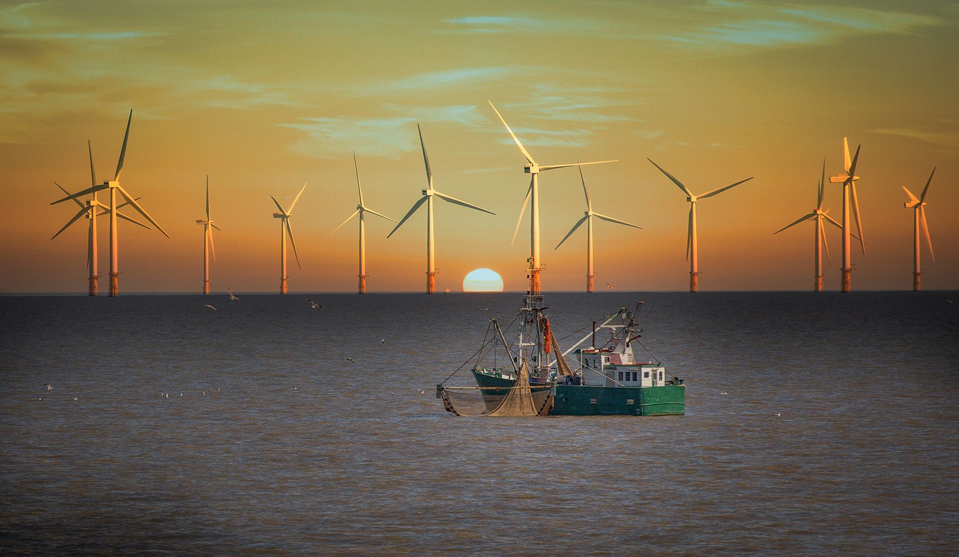 An image of a boat sailing by a wind farm